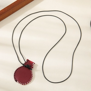 Close-up of deep red leather purse pendant with white hand-stitched edges and black cord