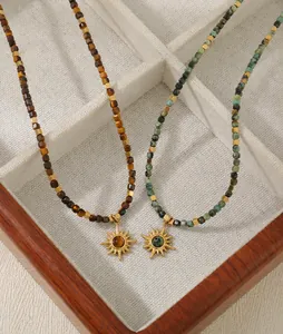 Detail of vintage beaded tiger eye necklaces with golden sunburst pendants on white velvet
