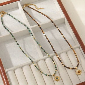 Tiger eye and turquoise beaded necklaces with gold sunflower pendants in a jewelry box