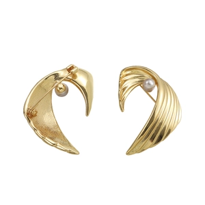 Vintage golden wing-shaped brooch with white pearl inlay and textured metallic finish
