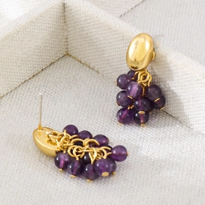 Detalle de pendientes de racimo de uva morada con pasadores dorados y cuentas de cristal