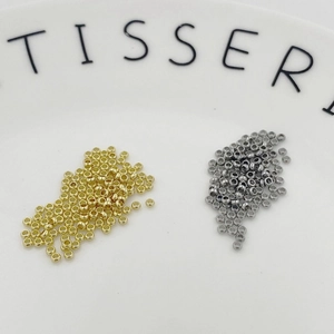 Macro detail of 2mm gold and silver crimp beads for DIY jewelry making and bracelet stringing