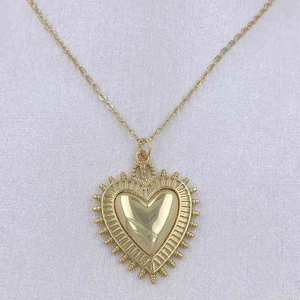 Close-up of gold heart pendant with radial textures and fine cable chain detail