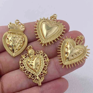 Detailed view of four vintage golden heart pendants with ornate religious style patterns