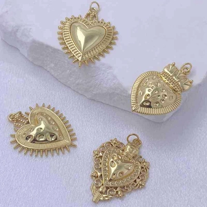 Polished gold heart pendants in four unique designs displayed on a marble stone surface