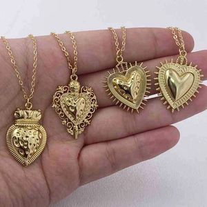 Detail view of four unique golden heart pendants with engraved patterns on fine chains