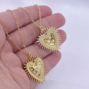 Macro shot of gold-plated sacred heart necklaces with crown and sunburst pendants
