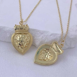 Detailed macro view of golden heart pendants with crown and strawberry textures