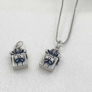 Vue détaillée du pendentif boîte cadeau argentée vintage avec nœud et couronne sur chaîne