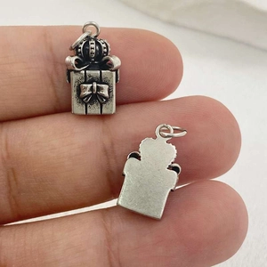 Détail d'un pendentif boîte cadeau couronne argentée vintage avec nœud, vues recto-verso