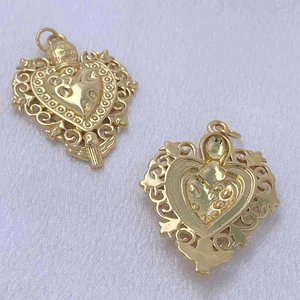 Macro detail of vintage hollow heart pendant with golden floral relief and flat back view