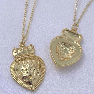 Golden heart necklace with crown detail and hammered texture on a silk background