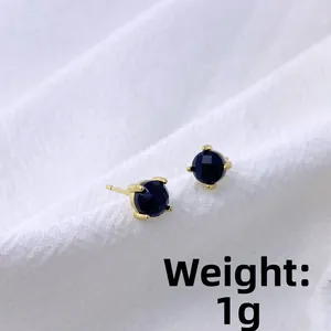 Close-up of minimalist black faceted stud earrings in gold setting, weight 1g