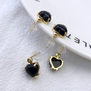 Detail of heart-shaped black onyx earrings with gold claw setting and small zircon