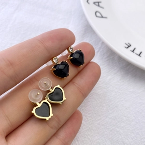 Macro view of gold heart stud earrings with black inlay and sparkling round cubic zirconia