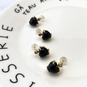 Macro shot of heart-shaped black stone earrings with gold metal and clear cubic zirconia