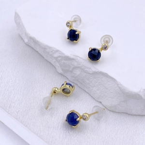 Elegant gold earrings set with round dark blue zircon and heart-shaped crystal accent