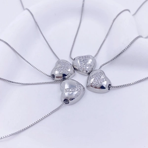 Macro detail of polished heart pendants with crystal letters K E M L on box chains
