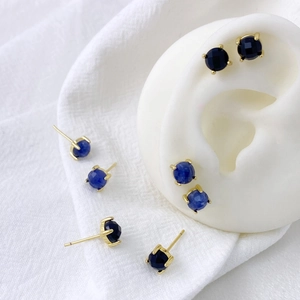 Detailed macro view of heart-shaped blue zircon and black onyx studs with gold prong settings