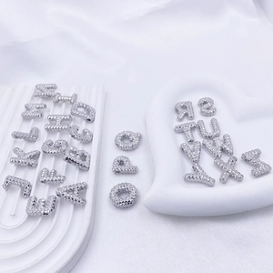 Makro-Detail von 26 silbernen Alphabet-Perlen mit strukturierter Oberfläche für DIY-Schmuck