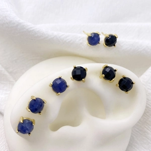 Detail of round blue and black zircon stud earrings with gold four-prong setting