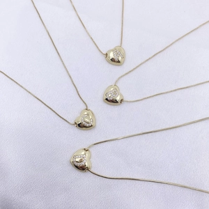 Detail of four golden heart-shaped initial necklaces A B C D with crystal inlays