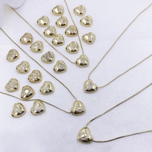 Detailed close-up of golden heart pendants with sparkling A-Z alphabet zircon stones