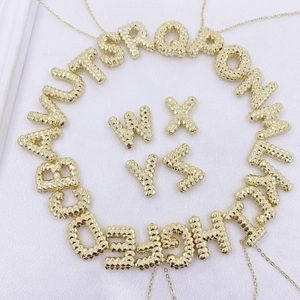 Makro-Detail von goldenen A-Z-Anhängern mit einzigartiger körniger Sandstruktur