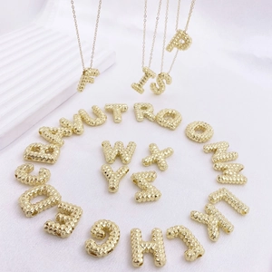 Detailansicht von 26 goldenen Buchstabenanhängern mit Nietentextur und feinen Halsketten