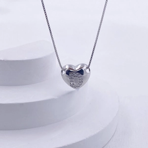 Macro shot of silver heart pendant with letter D diamond inlay on white stairs