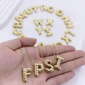 Detailansicht goldener Buchstabenanhänger mit Rautenmuster an feinen Halsketten