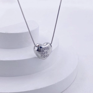 Macro detail of silver heart pendant with letter E crystal inlay on box chain