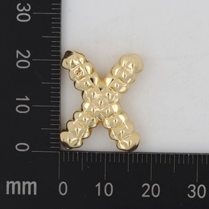 Makroaufnahme eines goldenen Buchstabe X Anhängers mit Gittermuster und Maßen