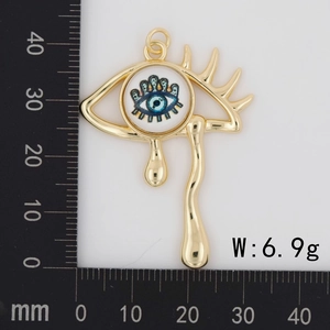 Detail view of gold-plated weeping eye pendant with teal eyeball on measurement scale