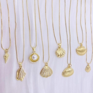 Goldene Muschelkette Kollektion mit Perlen und Kristallen auf weißem strukturiertem Stoff