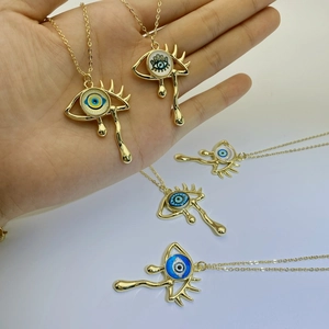 Detail of artistic evil eye teardrop pendants in gold finish with colorful enamel details