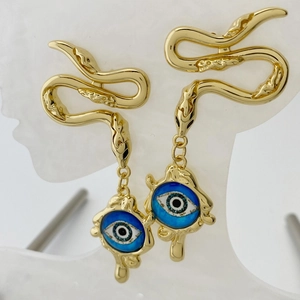 Macro detail of golden snake earring with blue evil eye charm and textured scales