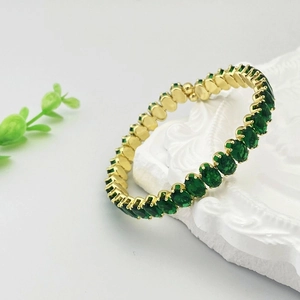 Détail du bracelet doré ajustable serti de zircons verts ovales avec monture à griffes