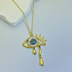 Macro shot of gold-plated evil eye necklace with tear drop pendant on stone background