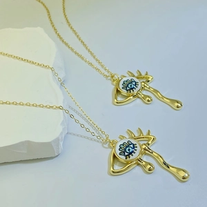 Macro shot of gold teardrop evil eye pendants on delicate chains over stone props