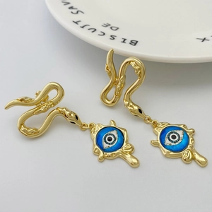 Detailed view of gold snake earrings featuring a blue evil eye charm on a grey backdrop