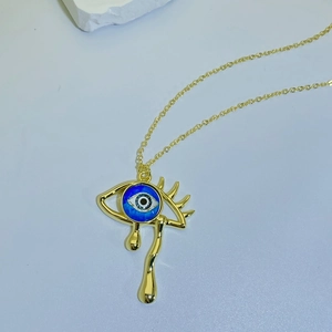 Detail of gold weeping eye pendant with blue evil eye stone on minimalist chain