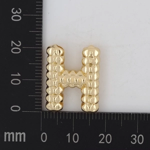 Makroaufnahme von goldenem H-Anhänger mit 3D-Perlenstruktur und Politur