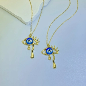 Detailed view of evil eye teardrop necklaces with blue enamel and gold finish charms