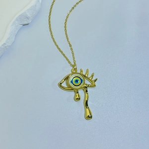 Detail of evil eye pendant in gold finish with fluid gold teardrops on a necklace