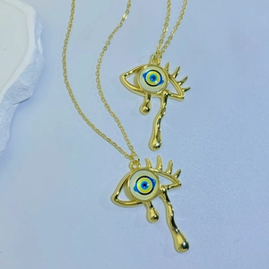 Detailed macro view of golden weeping eye pendants with colorful evil eye center accents