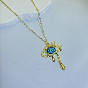 Detailed close-up of gold vintage weeping eye pendant necklace with blue iris detail