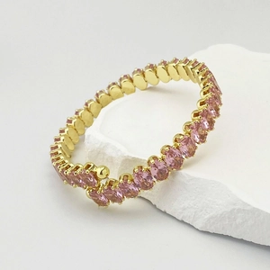 Détail d'un bracelet spirale doré orné de zircons cubiques roses ovales éclatants