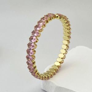Détail d'un bracelet doré réglable serti de pierres de zircone roses de forme ovale