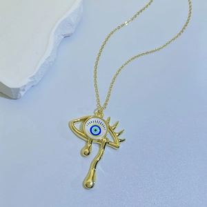 Macro view of teardrop evil eye necklace in gold finish on a minimalist stone